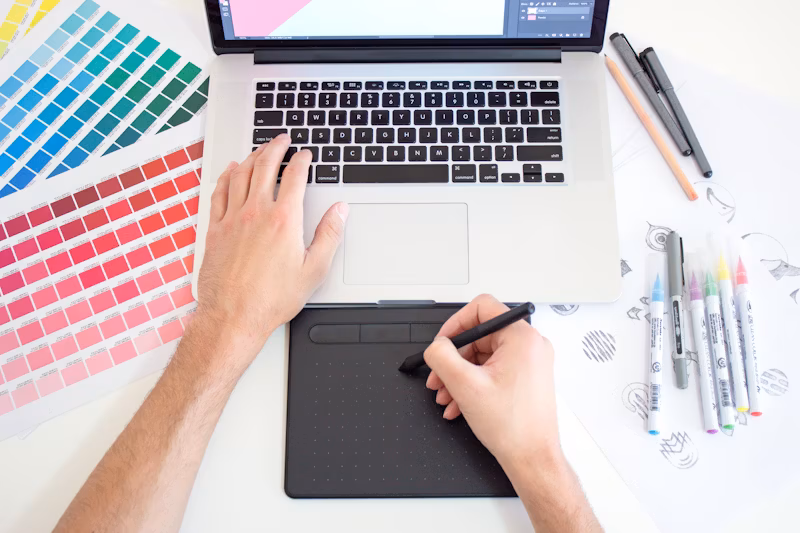 Manos de un diseñador trabajando en un portátil y un lápiz digital